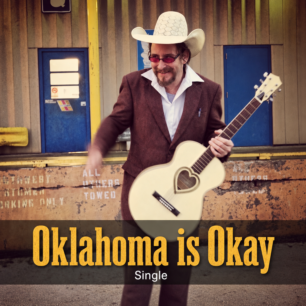 Oklahoma is Okay single artwork: thefatherphil in a cowboy hat with his guitar on the freight dock